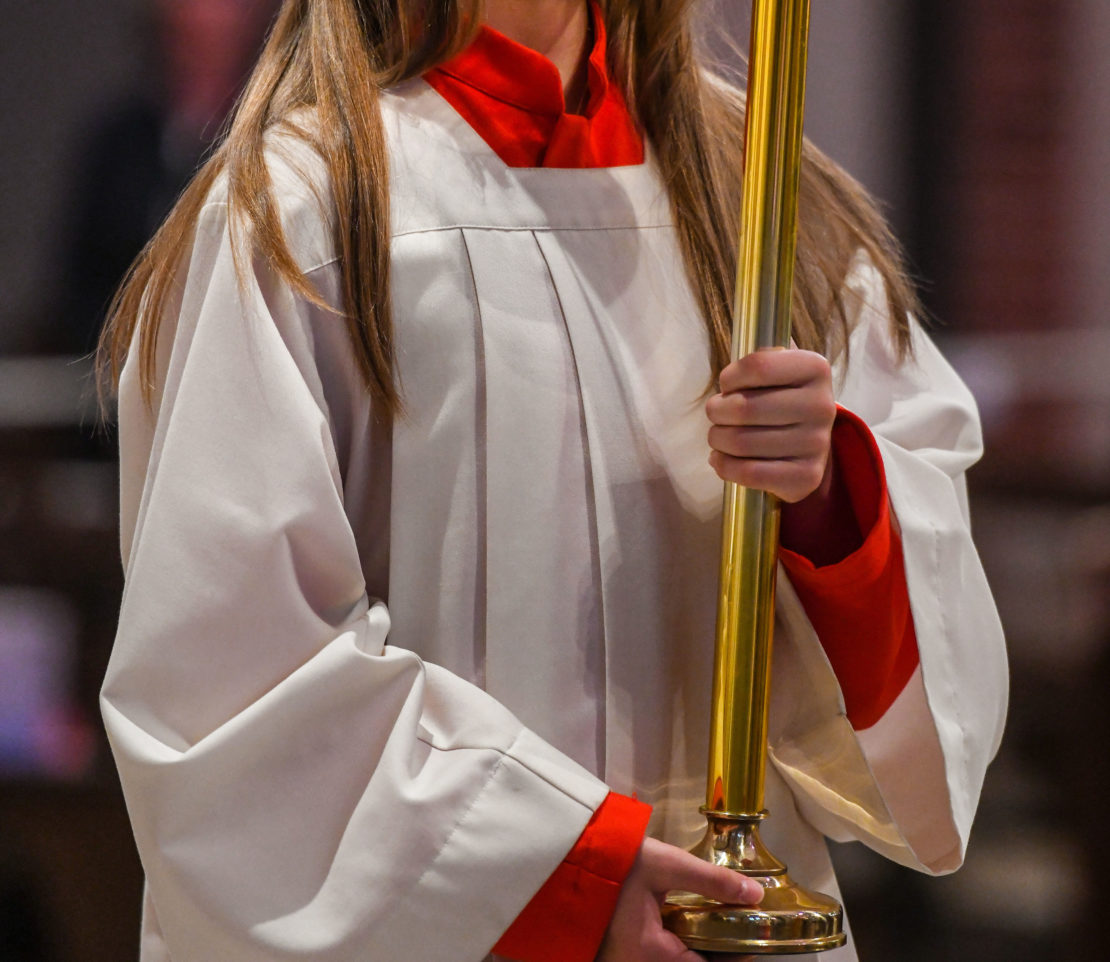 Eine Ministrantin hält den Leuchter bei der Messe zur Feier der Erstkommunion am 21. Juni 2020 in einer Kirche in Bonn.