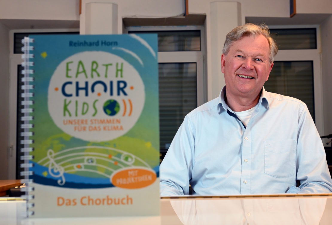 Reinhard Horn präsentiert in seinem Tonstudio in Lippstadt das Songbuch zum neuen Musikprojekt „EARTH•​CHOIR•​KIDS – Unsere Stimmen für das Klima“. (Foto: Patrick Kleibold)