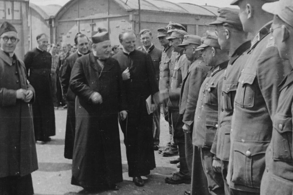 Stacheldrahtseminar von Chartres 1945-47, links neben Franz Stock der Apostolische Nuntius Roncalli und spätere Papst Johannes XXIII. bei einem seiner vier Besuche im Lager (rechts Laien-Dozenten).